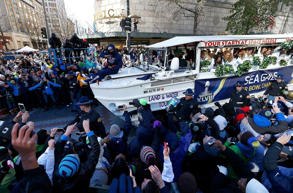 Marshawn Lynch of the Seattle Seahawks throws out Skittles to fans during a parade to celebrate their victory in Super Bowl XLVIII.
