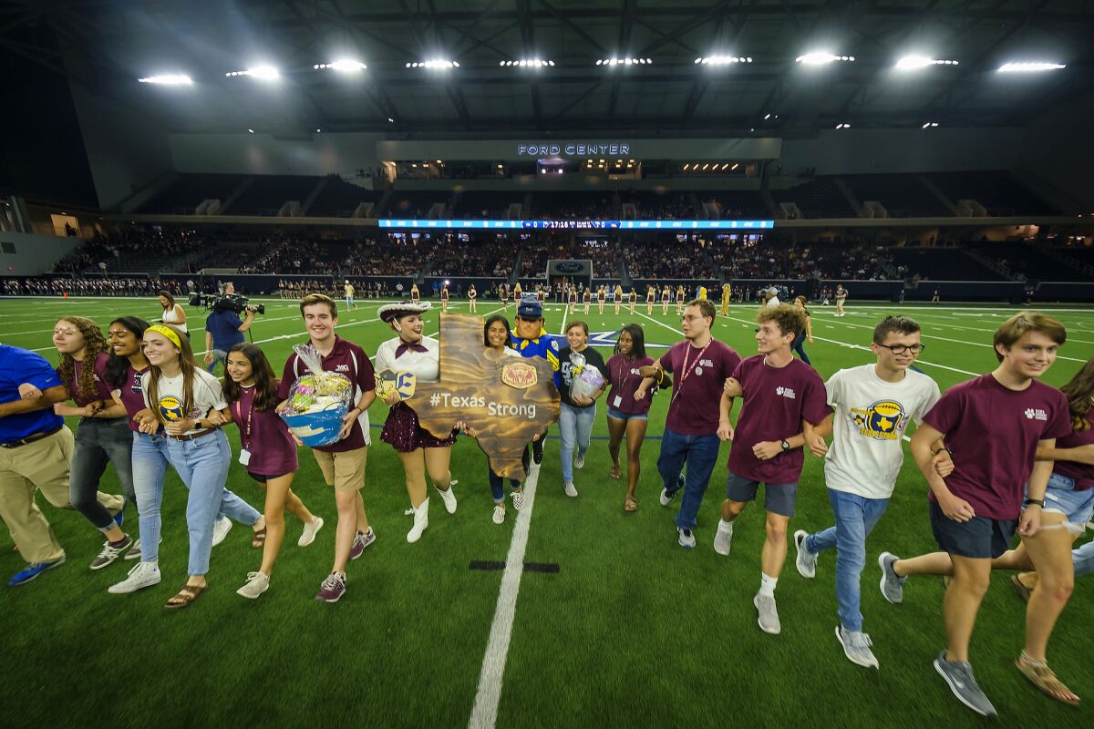 Student government representatives from Plano and El Paso Eastwood high schools lock arms and cross the field.