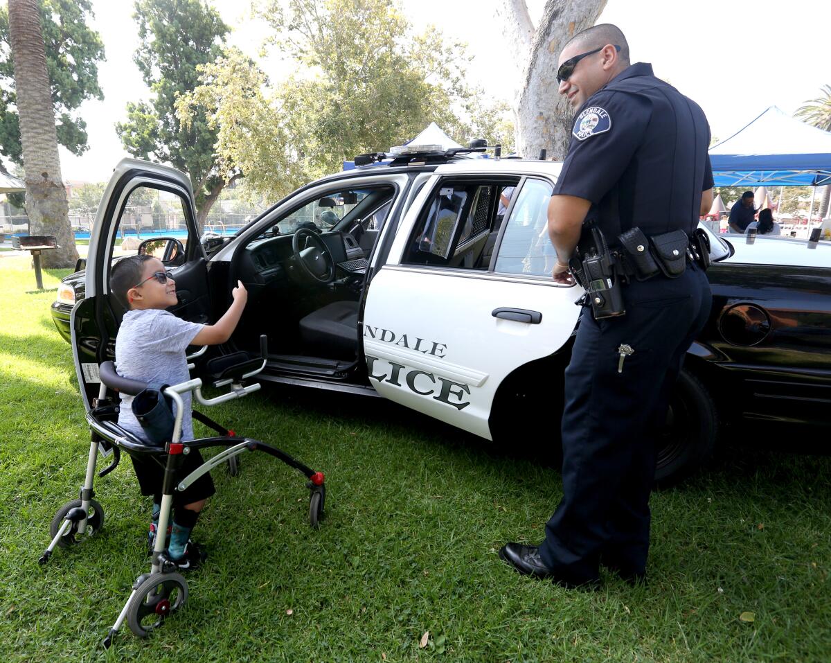 Glendale Police officer Varooj Karibyan, right, talks with Danny Lopez, 7, of Reseda, during a ribbon-cutting ceremony at Maple Park for the new all-inclusive playground.