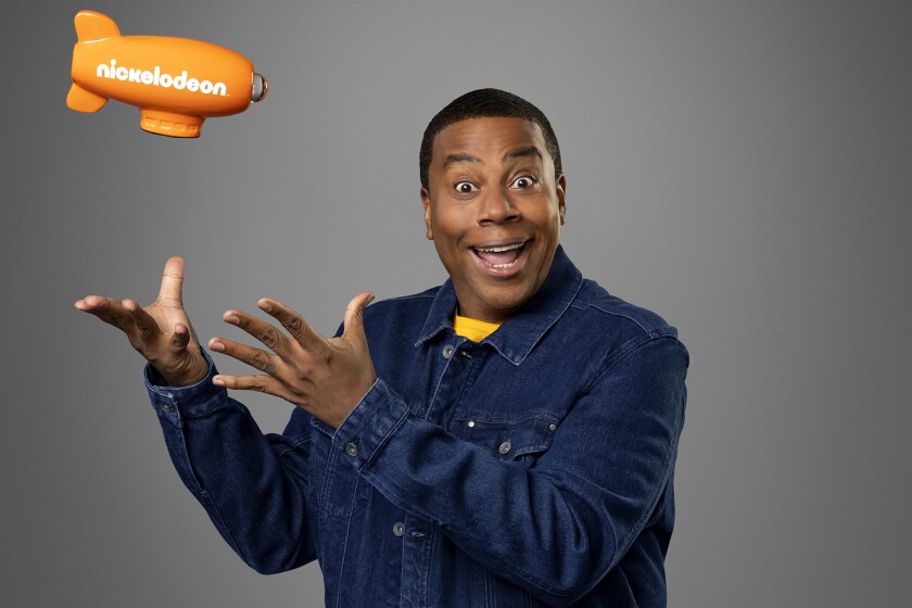 Kenan Thompson gestures upward at a small blimp