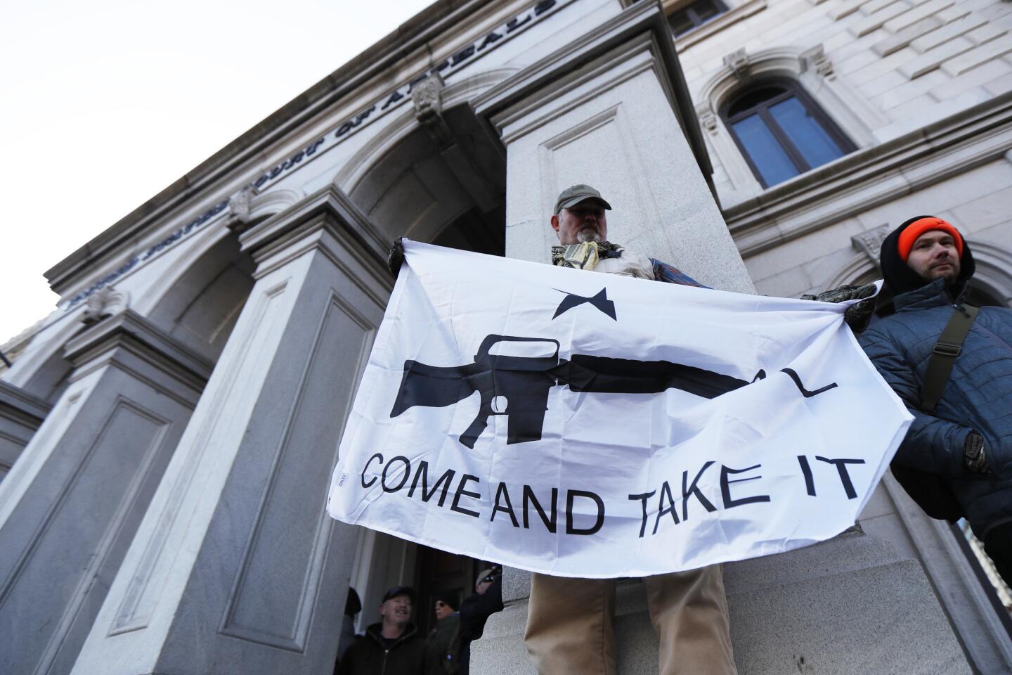 A demonstrator holds a "Come and Take It" banner.