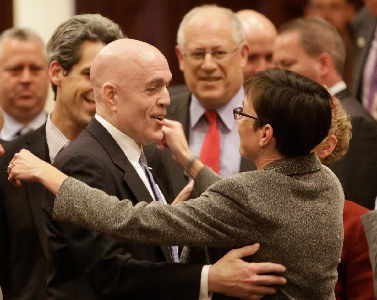 Illinois Rep. Greg Harris (D-Chicago), left, is congratulated by lawmakers as gay marriage legislation passes on the House floor Tuesday. Gov. Pat Quinn is center.
