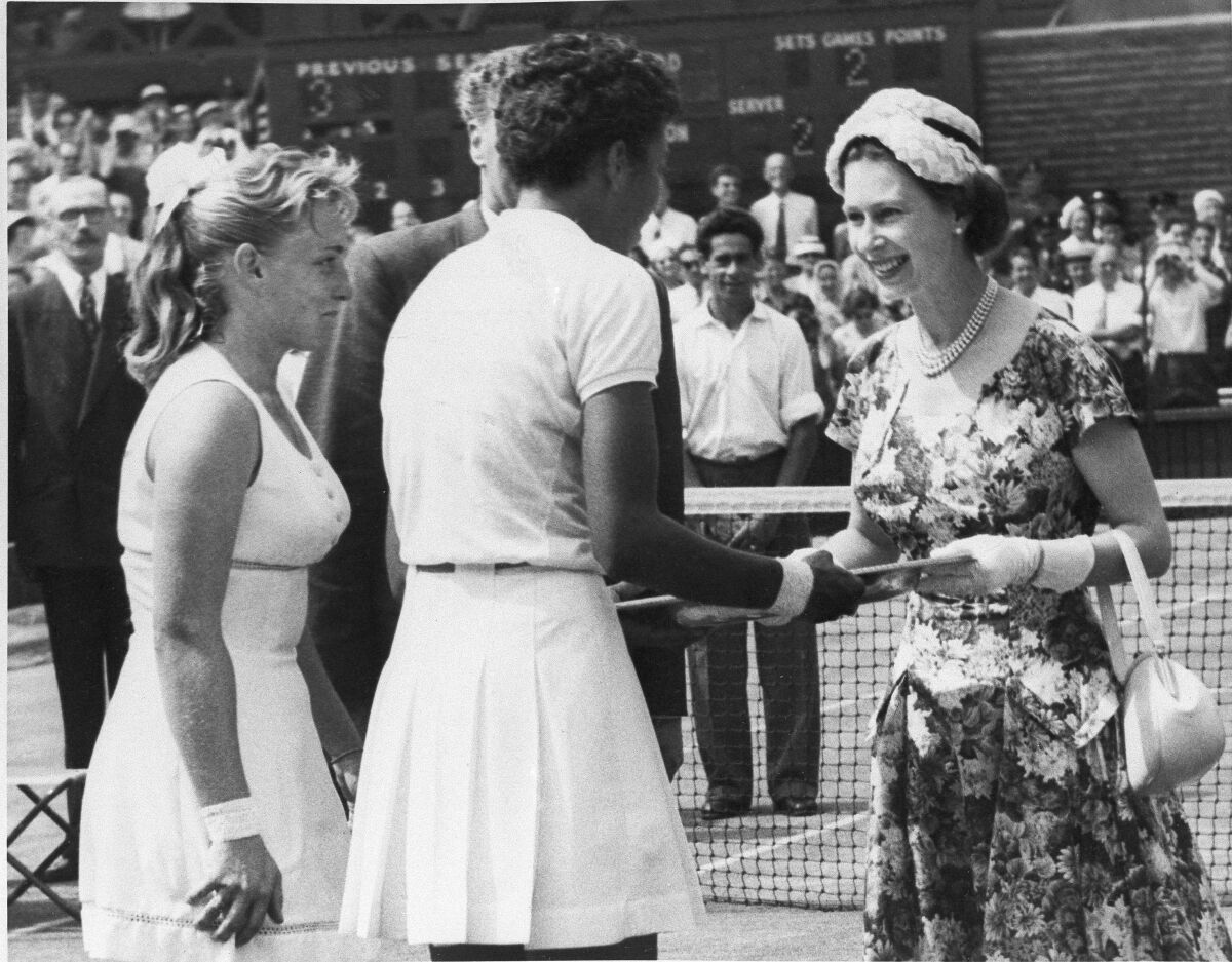 Queen Elizabeth presents the winner's trophy to Althea Gibson, center, after her victory over Darlene Hard.