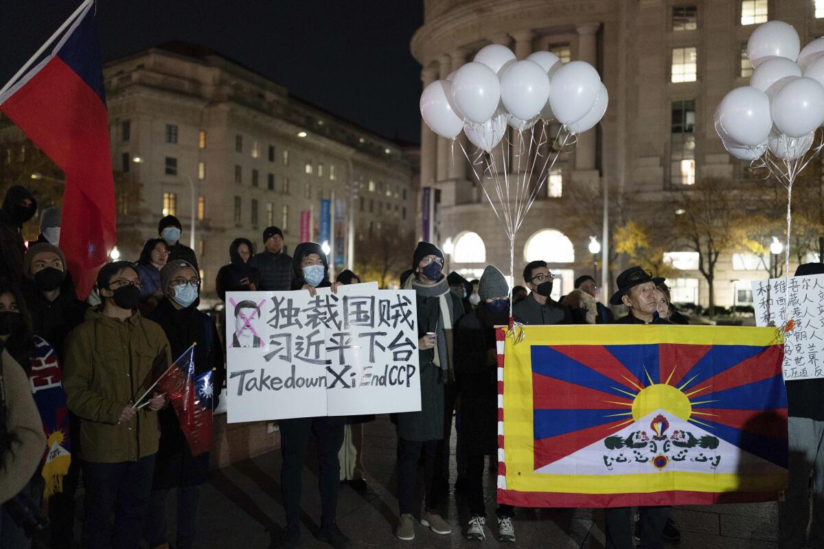 Protesters gathered, one with a sign that reads "Take down Xi. End CCP"