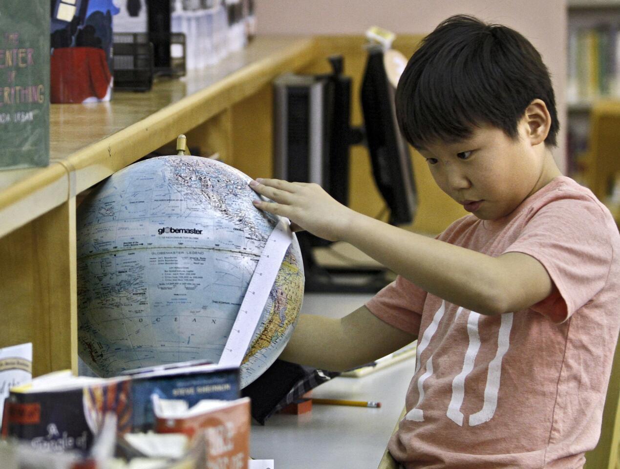 Nathan Kim, 9 of La Crescenta, measures the circumference of a globe during the How Tall Is It? scavenger hunt at the Montrose Library in Montrose on Wednesday, January 15, 2014. Participating children had to find 13 locations within the library and measure items mentioned in the clues. Once they finished the hunt, they received a small prize.