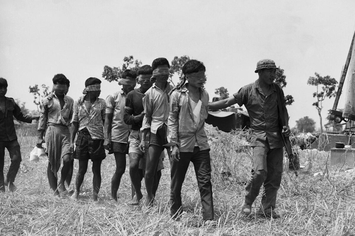 A South Vietnamese soldier takes a group of blindfolded Khmer Rouge prisoners to an interrogation center in Kompong Trach, Cambodia, in 1972.