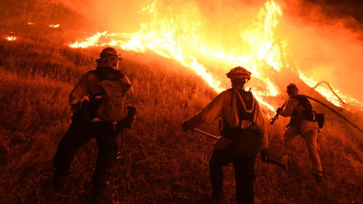 Firefighters conduct a controlled burn to defend houses against flames from the Ranch fire, part of the Mendocino Complex fire, as it spread toward the town of Upper Lake, Calif.