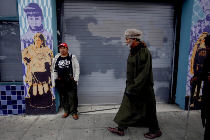Elias Nolasco, left, 39, of Oakland stands near the site of the warehouse fire as poet Alfred Hayes, right, 69, of Oakland, walks to his dentist appointment in Oakland on Wedneday. Residents described Fruitvale, situated in the flats south of downtown between two freeways, as a largely Latino district of working-class families and small shops.