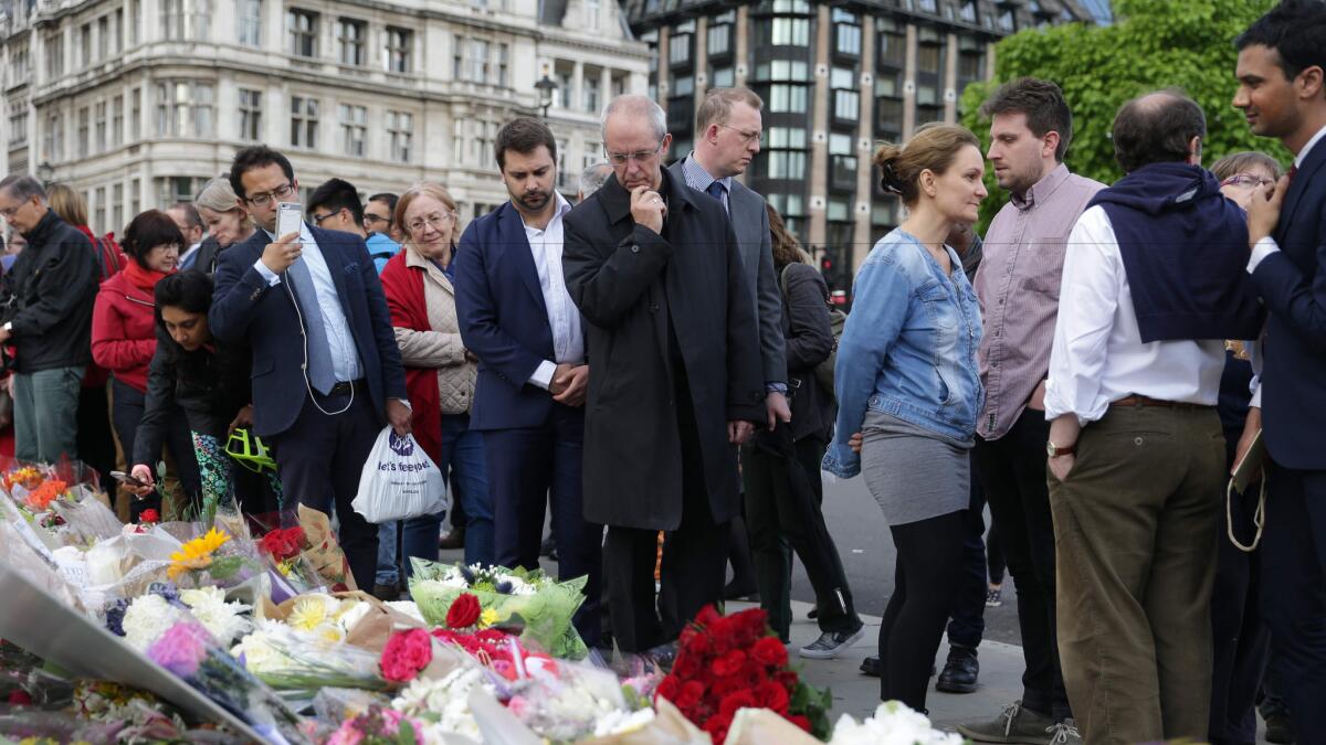 Archbishop of Canterbury Justin Welby, center, and others pause at tributes laid in remembrance of slain British lawmaker Jo Cox in London on June 17, 2016.