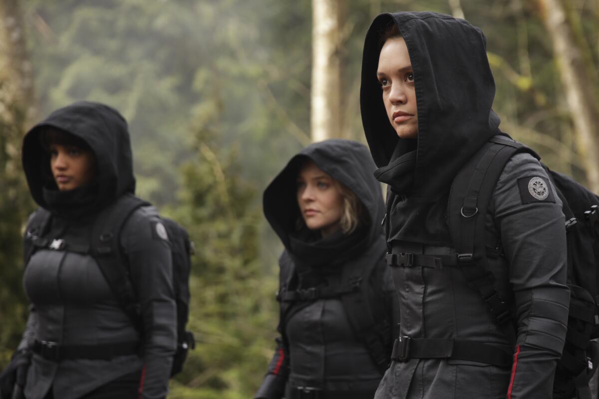 three women in hooded tactical gear in the woods