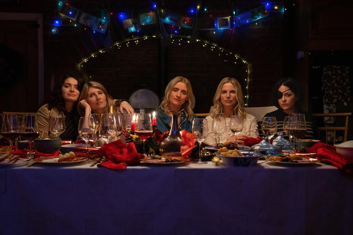 Five women sit at a festive dinner table.