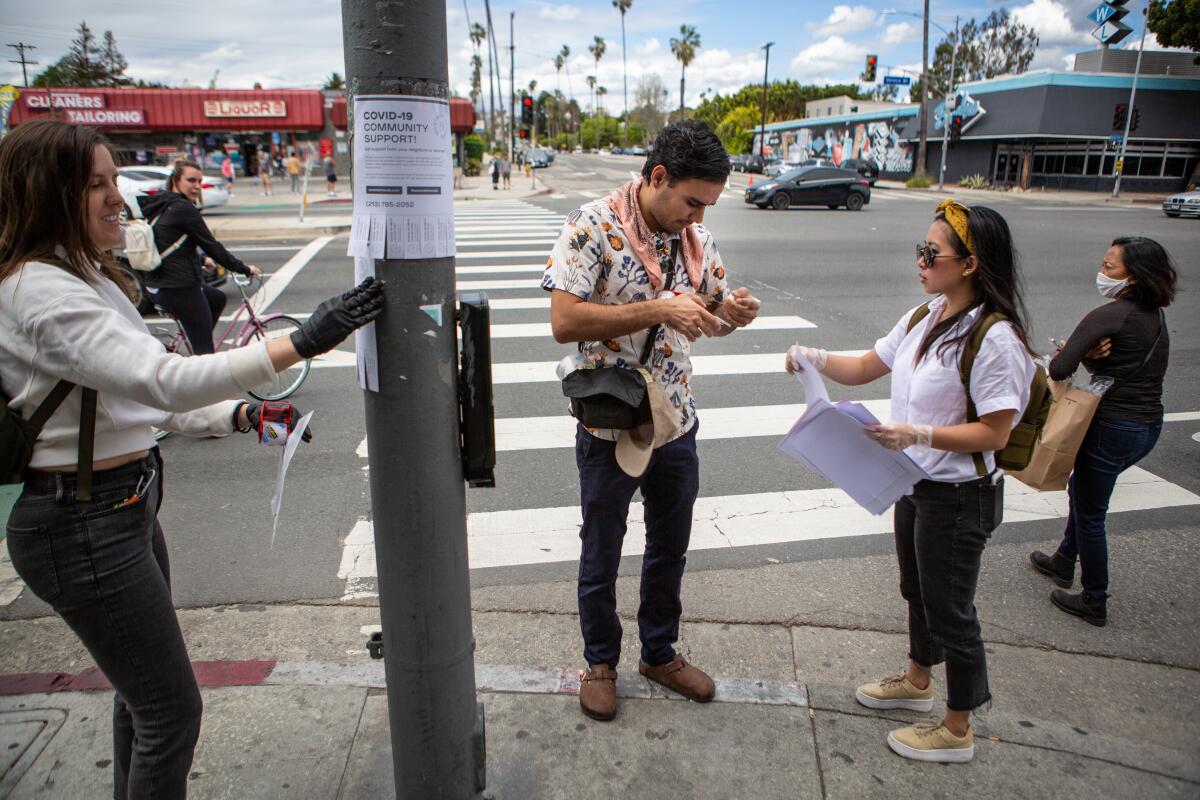 Annie Bickerton, left, Richard Tamayo and Cristin Lim post fliers with offers of help to neighbors throughout Mar Vista.