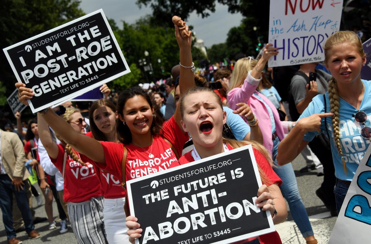 Demonstrators march carrying signs that read "The Future is Anti-Abortion" and "I Am the Post-Roe Generation."