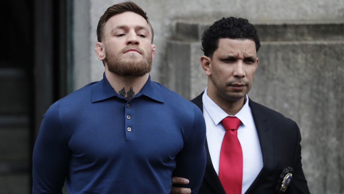 UFC star Conor McGregor is led by an official to an unmarked vehicle while leaving a precinct of the New York Police Department on April 6.
