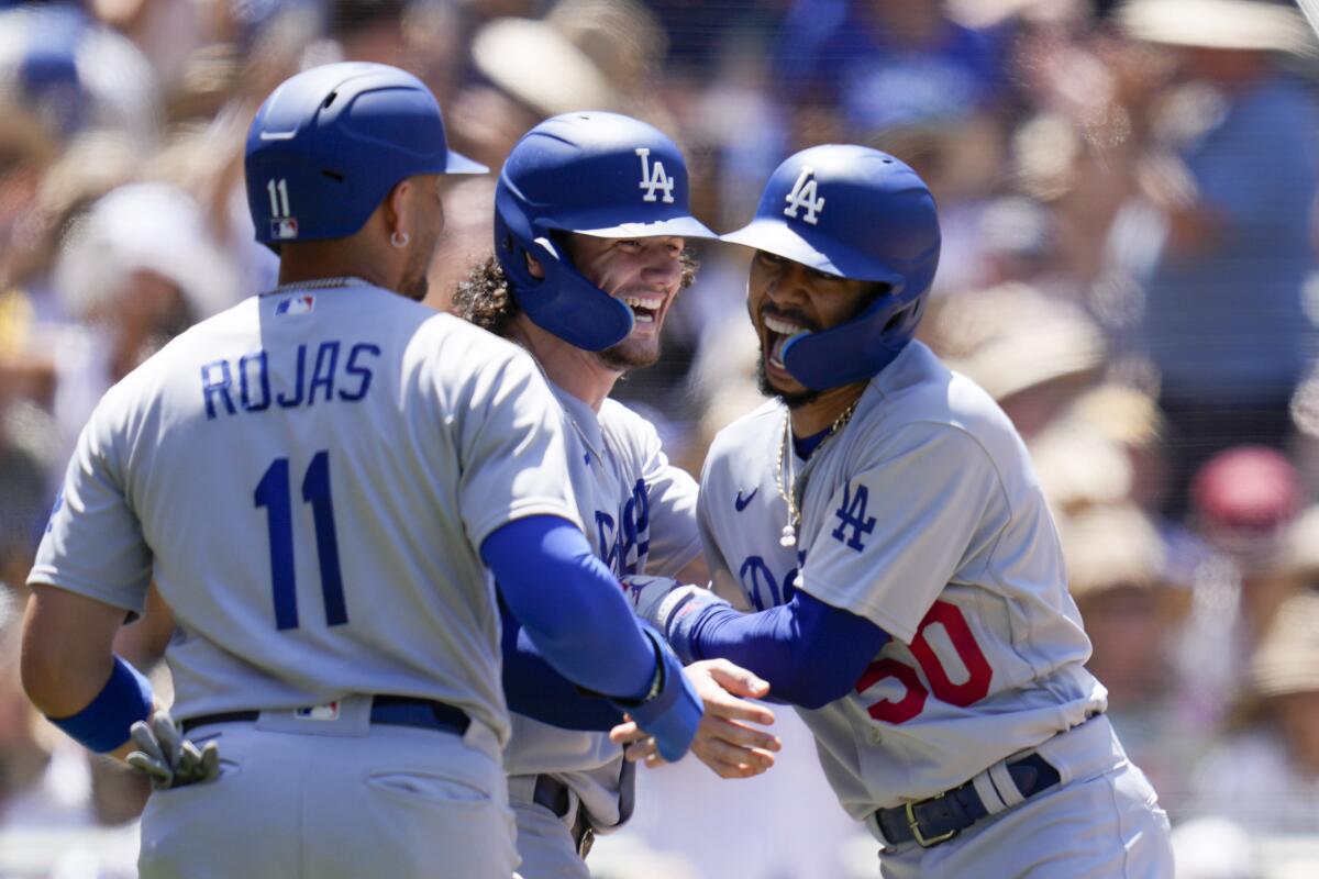 Mookie Betts celebrates with Dodgers teammates James Outman and Miguel Rojas after hitting a grand slam.