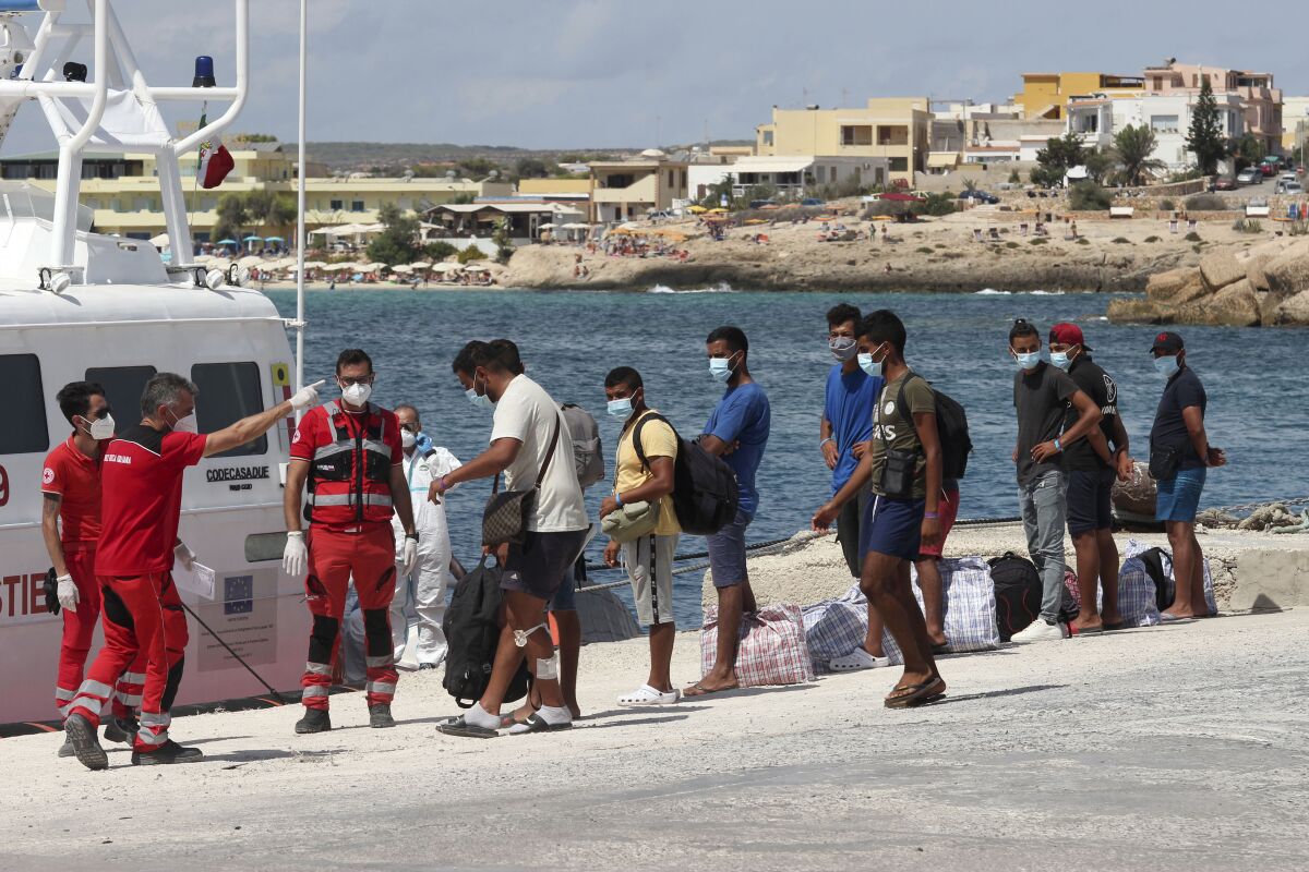 Migrants wait to board a coast guard ship that will take them to the GNV Rhapsody ferry moored off Lampedusa island, Italy, Saturday, Sept. 5 , 2020. Italian officials have been hastily chartered ferries and put other measures into place to fight severe overcrowding at migrant centers on the tiny island of Lampedusa. (AP Photo/Mauro Seminara)