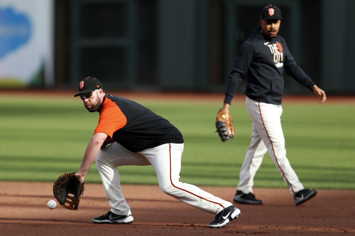 San Francisco Giants' Darin Ruf, left, and LaMonte Wade Jr., right, field balls in the infield during a workout prior to Game 1 of a baseball National League Division Series against the Los Angeles Dodgers, Thursday, Oct. 7, 2021, in San Francisco. (AP Photo/Jed Jacobsohn)
