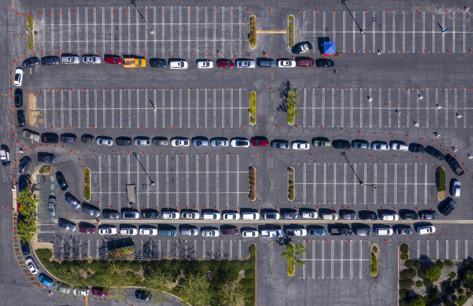 Aerial view shows a serpentine trail of cars winding around an empty parking lot.