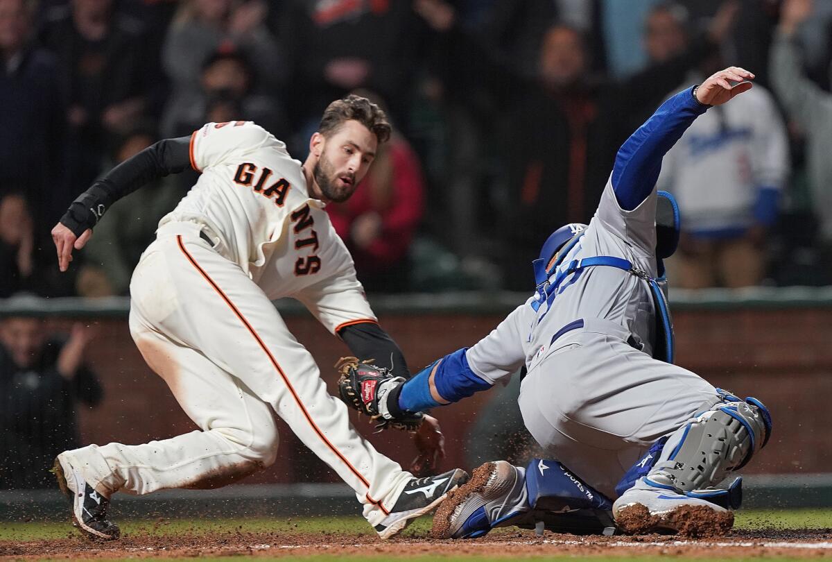 San Francisco Giants' Steven Duggar, left, scores the winning run sliding past the tag of Dodgers' Russell Martin in the bottom of the ninth inning on Wednesday in San Francisco.