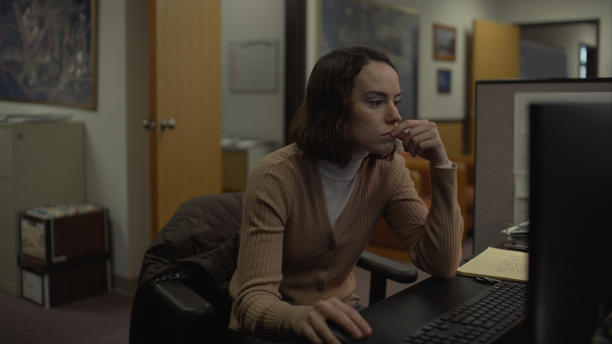 A woman leans over her desk toward her computer