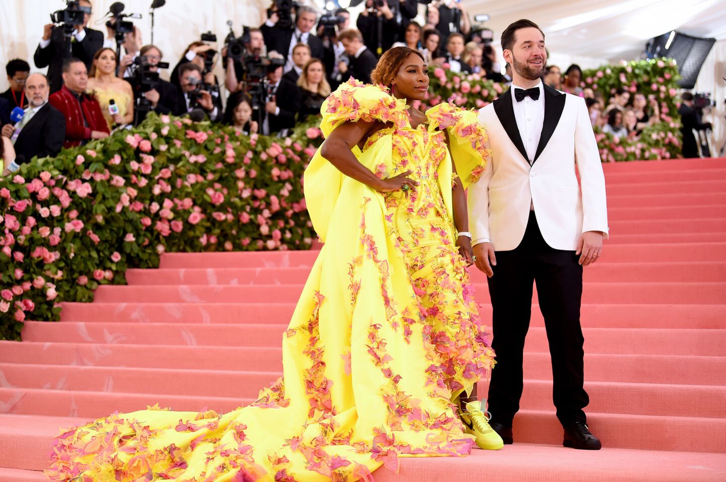 2019 Met Gala co-chair Serena Williams and husband Alexis Ohanian arrive. Instead of heels, the tennis star wears yellow Nike sneakers with her yellow custom Versace gown, which is festooned with pink, purple and yellow appliques resembling butterflies.