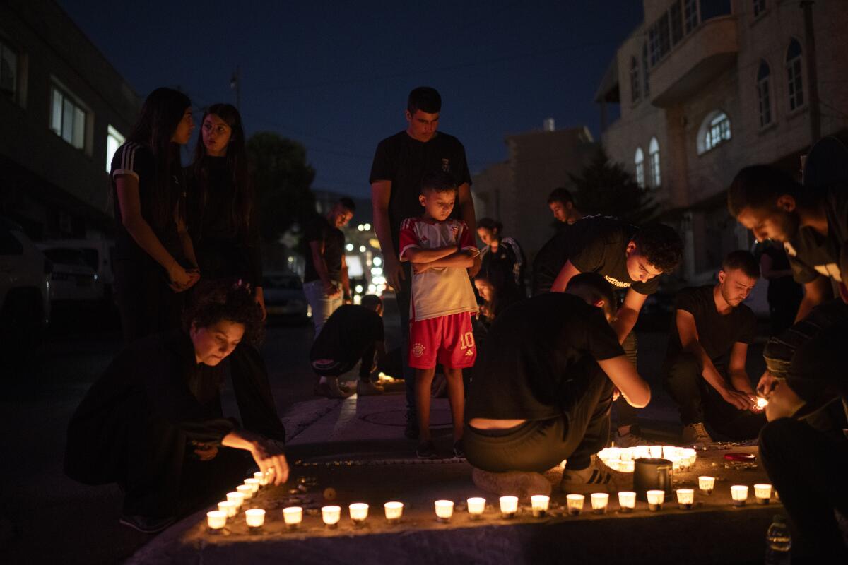 Children and adults surrounded by candles at a memorial service.