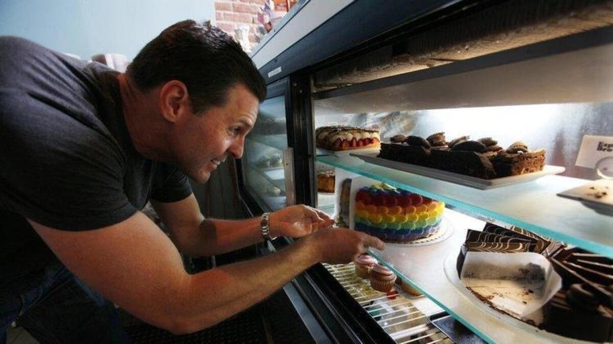 Christopher Stavros sets the rainbow cake back in the display case at Babycakes.