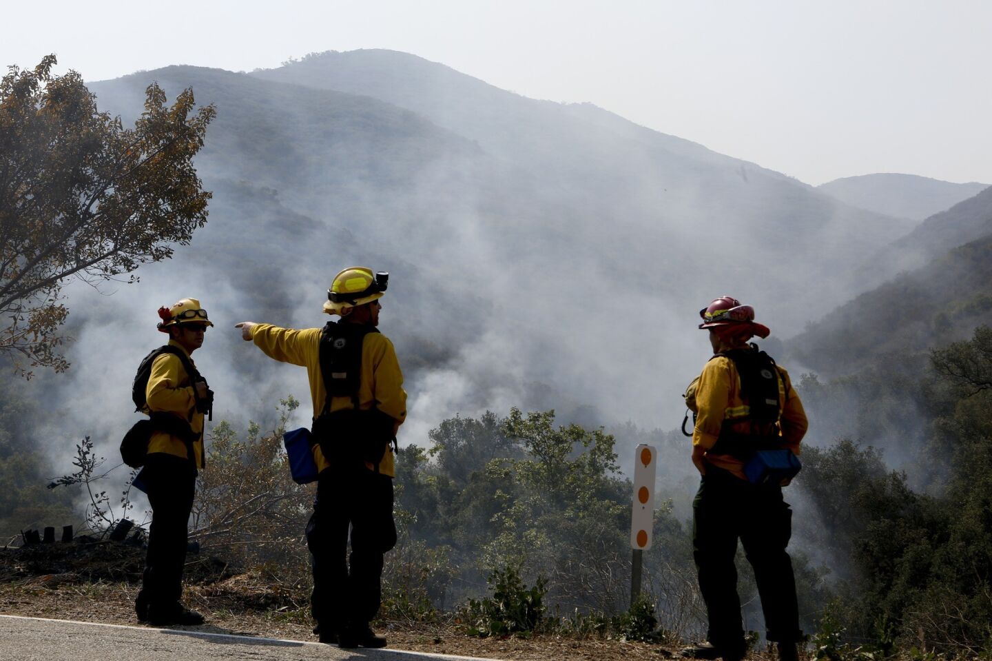 Firefighters keep an eye on a smoldering area along Potrero Road in Newbury Park where crews lit back fires last night to prevent further spread of the Springs fire.