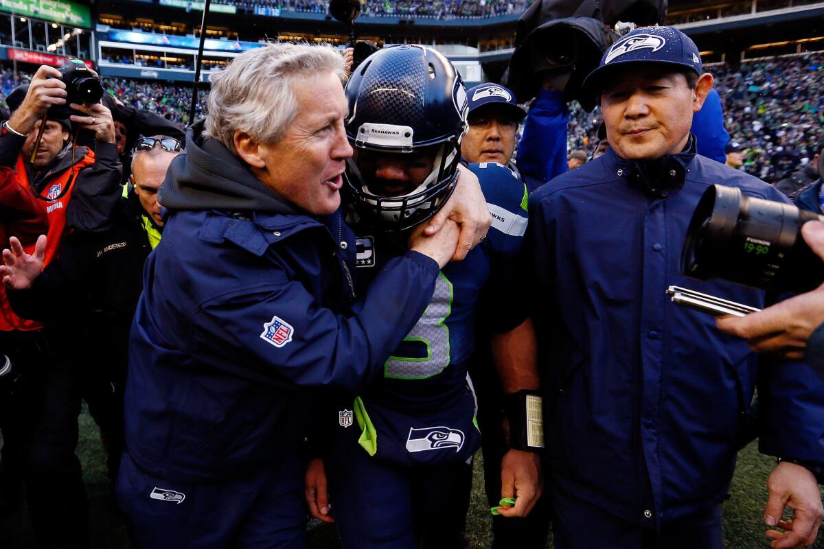 Seahawks Coach Pete Carroll embraces quarterback Russell Wilson, who led Seattle to an overtime victory against the Green Bay Packers on Sunday in the NFC championship game by wiping out a 16-point deficit.