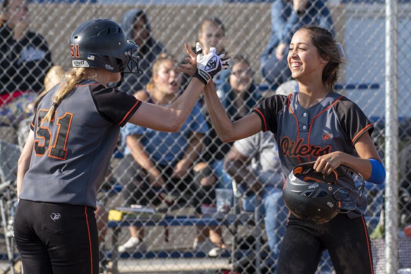 Huntington Beach's Shelbi Ortiz high fives Allee Bunker after scoring on an obstruction call at the plate in a CIF Southern Section Division 1 quarterfinal game on May 24, 2018. After a conference with the umpires, the call was overturned.