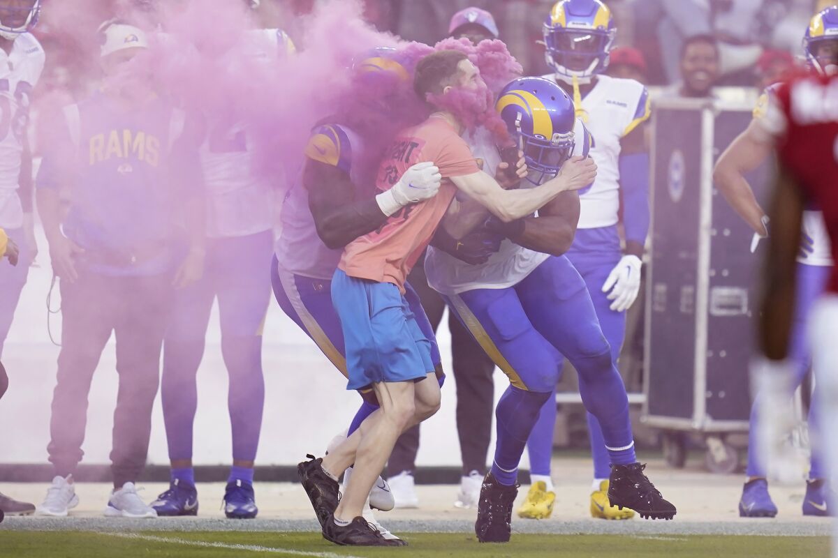 A protester is hit by Rams' Takkarist McKinley, middle left, and linebacker Bobby Wagner during a game against the 49ers.