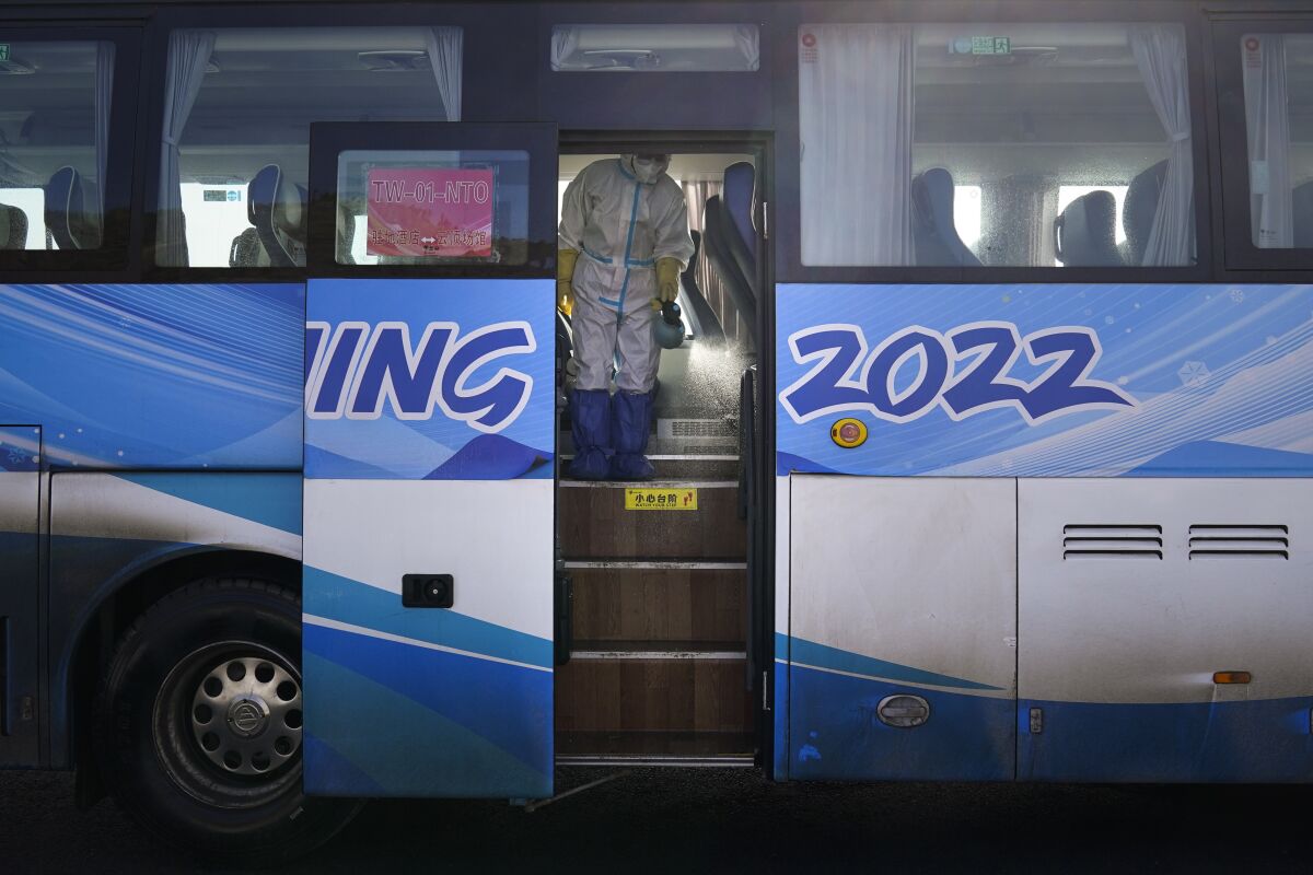 A worker in protective gear disinfects an Olympic shuttle bus ahead of the 2022 Winter Olympics.
