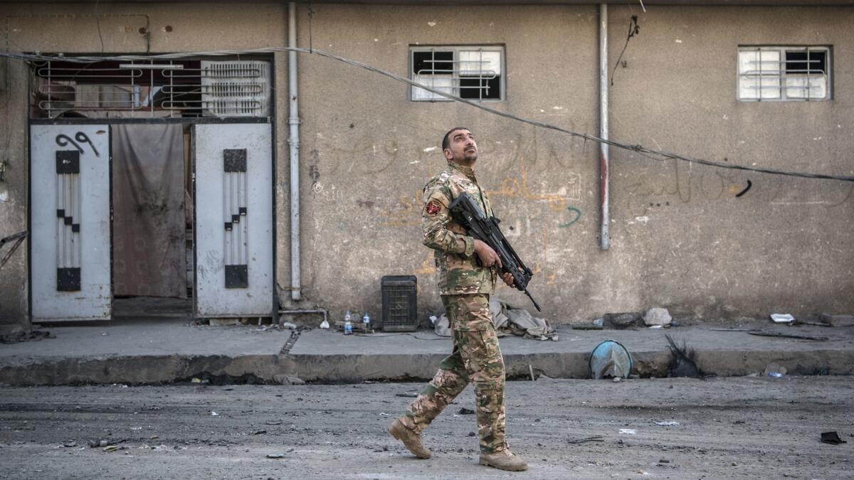 An Iraqi Emergency Response Division soldier looks to the sky after hearing a noise believed to be from an Islamic State drone during fighting in west Mosul on April 7 in Mosul, Iraq.