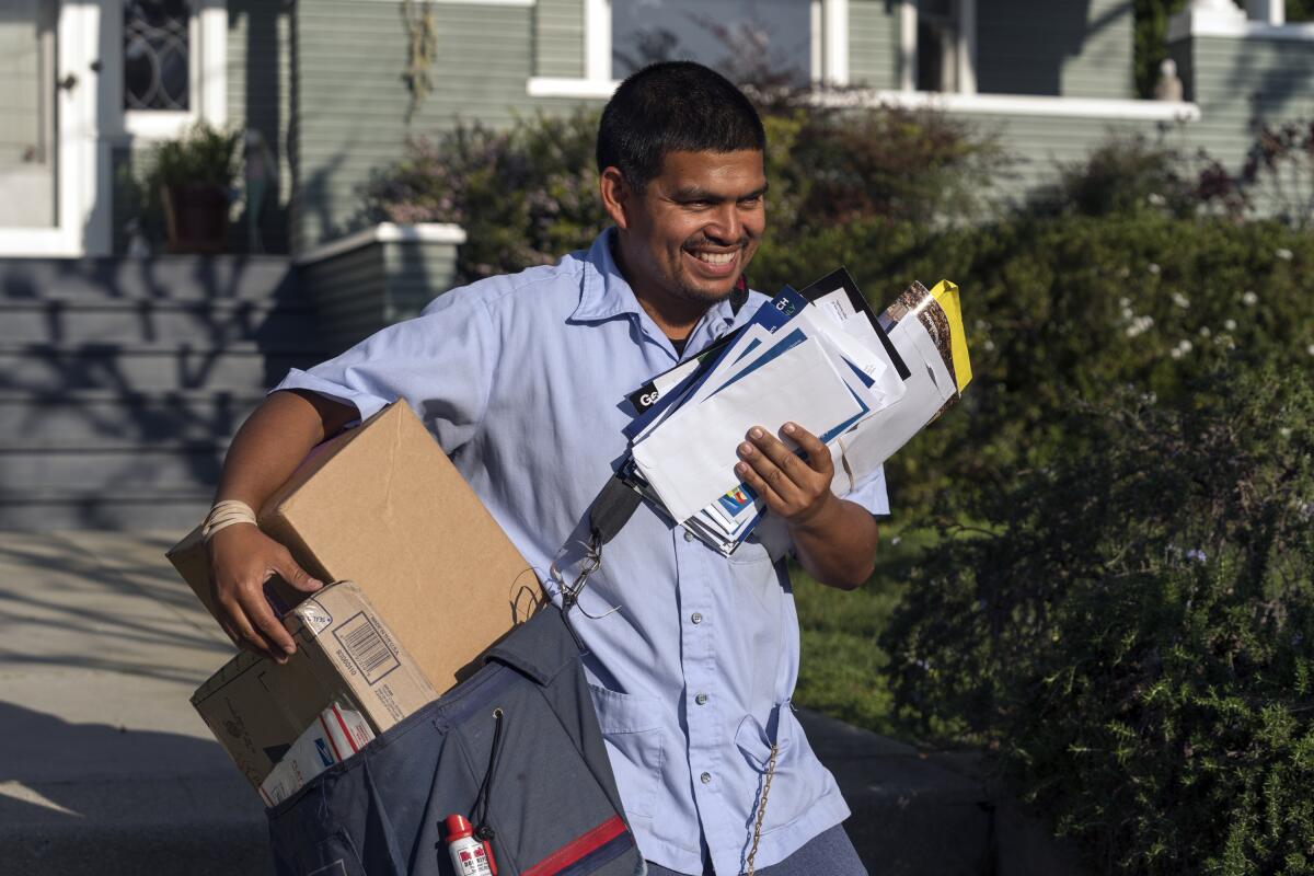 ARCHIVO - El cartero del Servicio Postal de Estados Unidos, Gabriel Peña, carga el correo en Los Ángeles