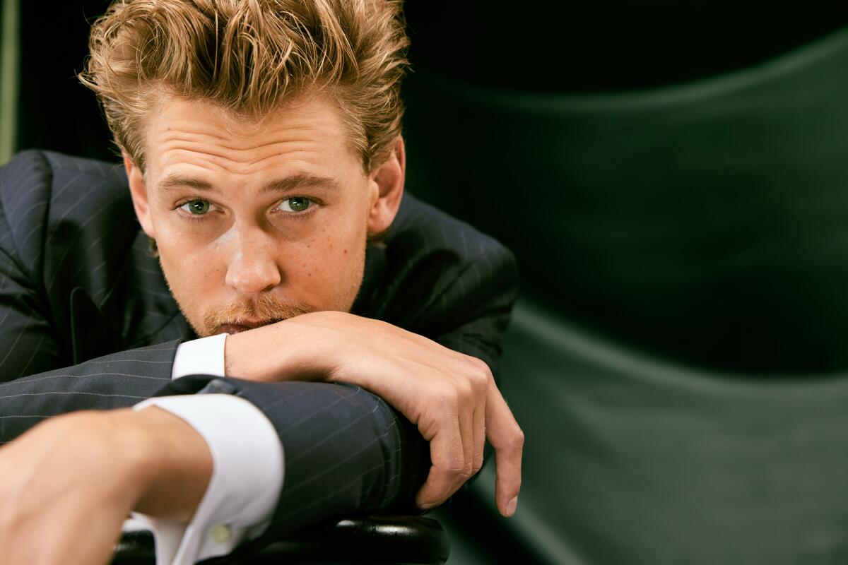 Austin Butler leans on a table, chin resting on his arms.