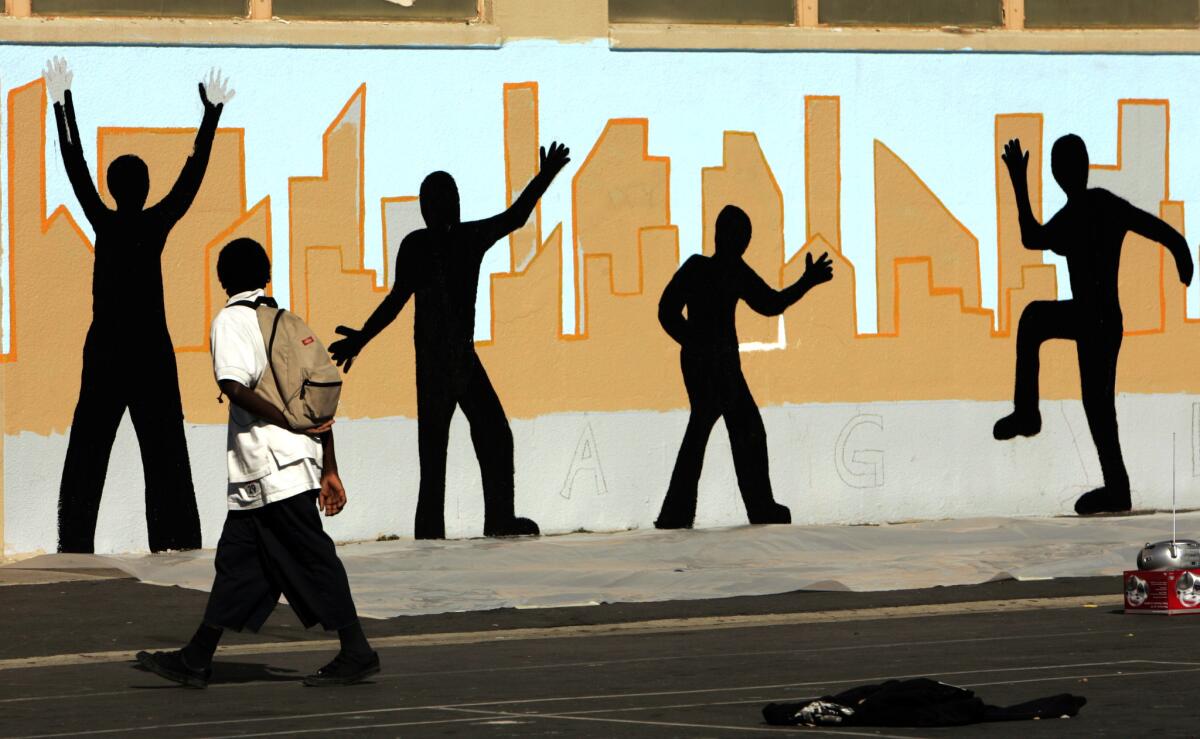 A student walks past a mural at Markham Middle School in Watts, where several African American parents allege Latino administrators there are unfairly sending their students home in off-the-books suspensions.