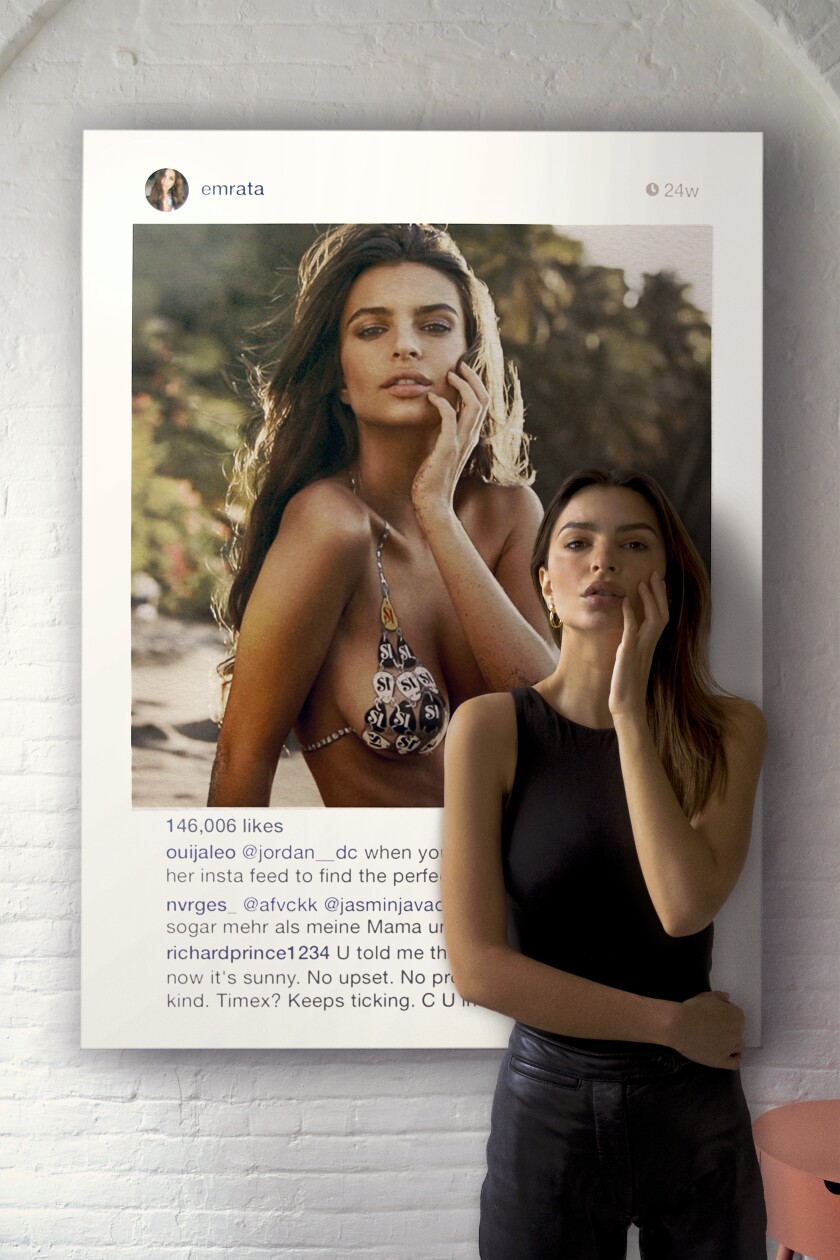 Emily Ratajkowski stands in front of a photo of herself.