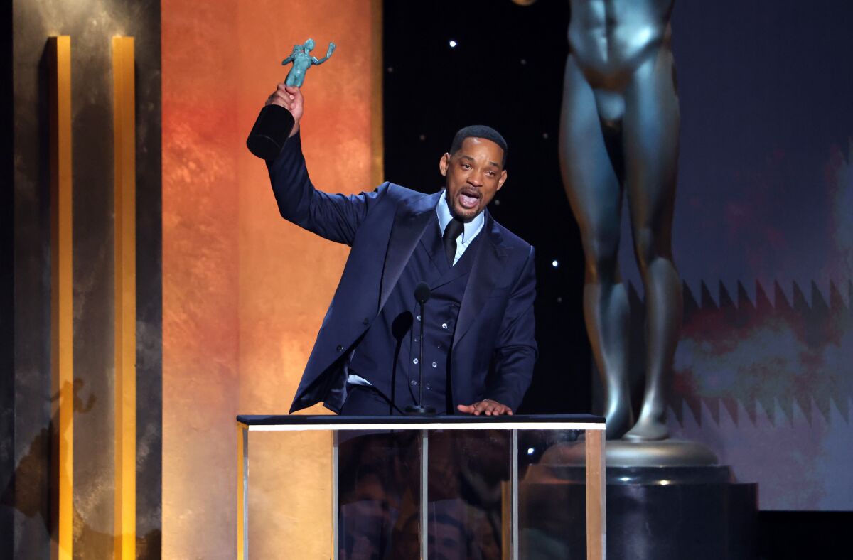 Will Smith hoists his SAG Award statuette above his head.