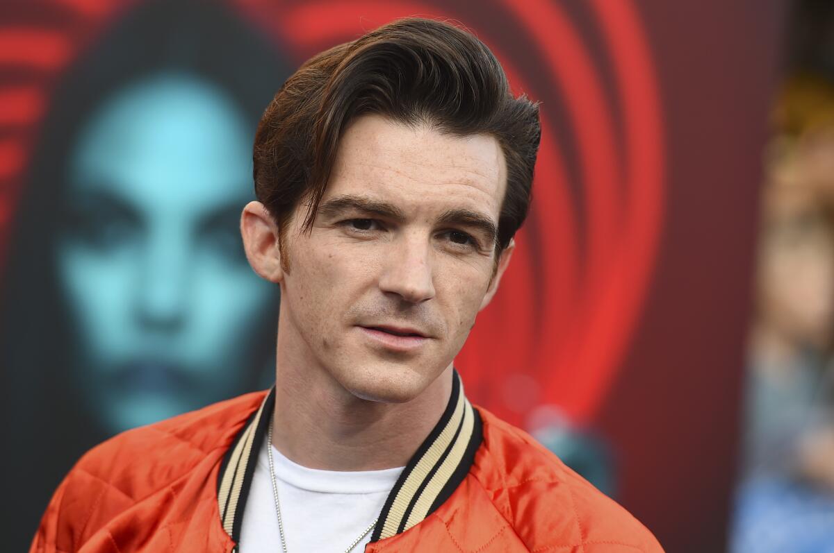 Drake Bell wearing a red jacket and a white T-shirt.