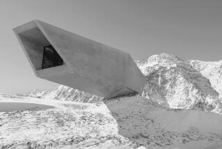 A long, rectangular concrete structure cantilevers out over thin air against the backdrop of snow-covered mountains.
