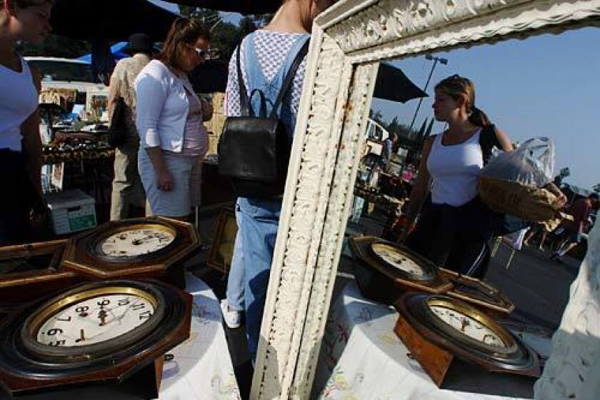 A mirror at the Pasadena City College flea market reflects shoppers looking for treasures amongst the different vendors' wares.