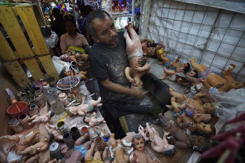 Maximino Vertiz Quintanilla repairs a customer's baby Jesus statue inside his store in preparation for the feast of the "Dia de la Candelaria" or Candlemas in Mexico City, Wednesday, Jan. 25, 2023. As Mexicans prepare to celebrate Candlemas people bring in their Baby Jesus figures for major repairs. (AP Photo/Marco Ugarte)