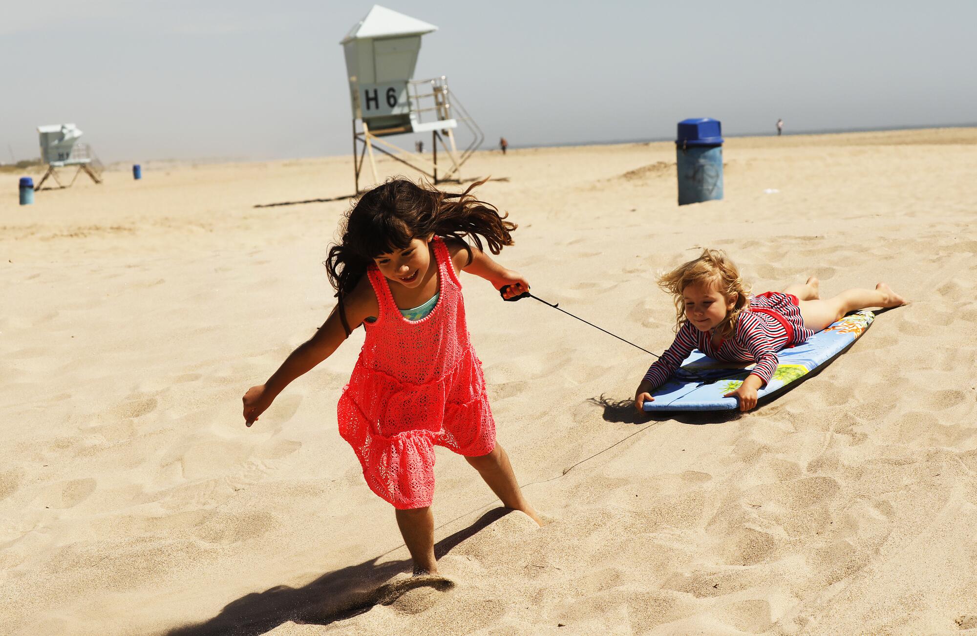 Emily Enholm, 7, and her sister, Hazel, 4, play on the sand at Hueneme Beach. Ventura agreed to allow people to use the city’s beaches, pier, promenade and parks as long as they keep their distance from one another and remain on the move.