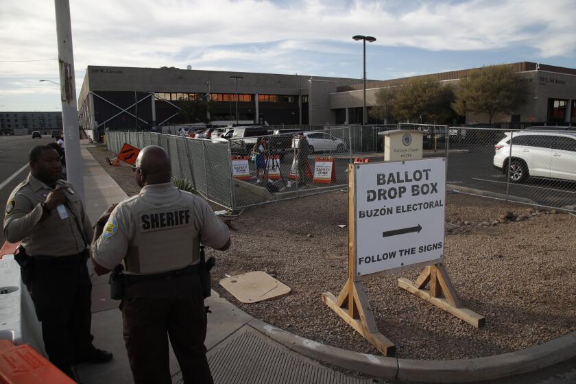 Phoenix, AZ - November 7: Security guards watch over a ballot drop box on Monday, Nov. 7, 2022 in Phoenix, AZ. (Gina Ferazzi / Los Angeles Times)