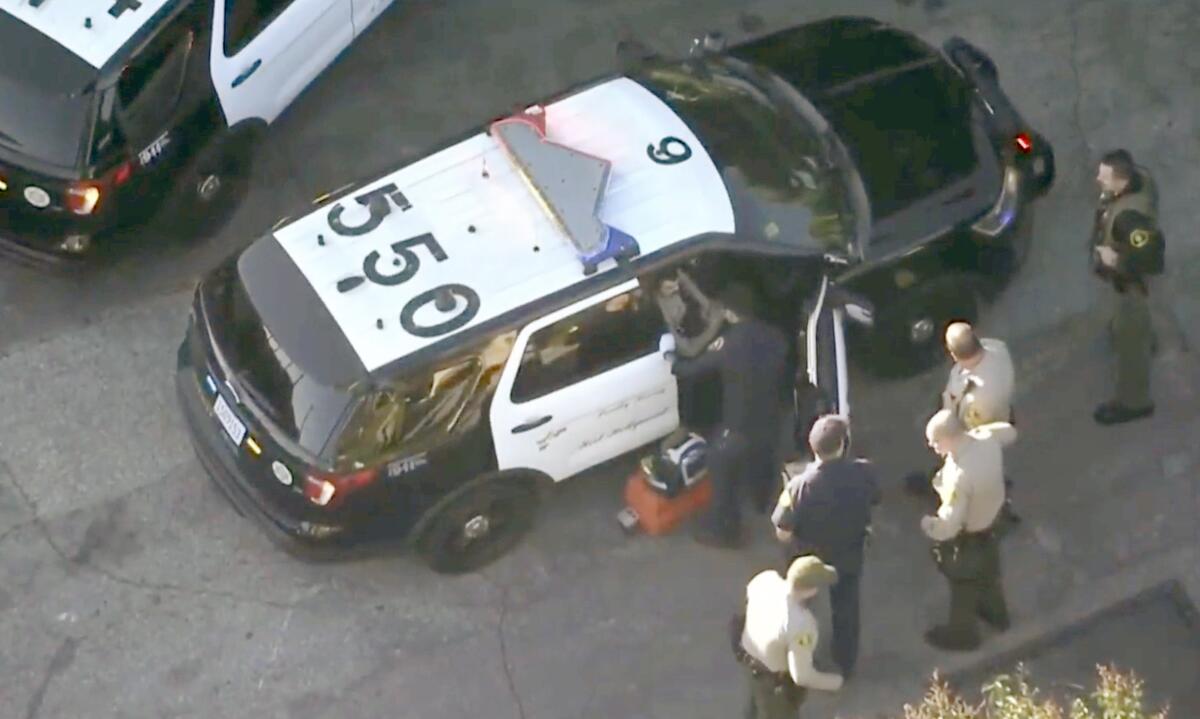Aerial view of a sheriff's department vehicle with people in uniform outside it.