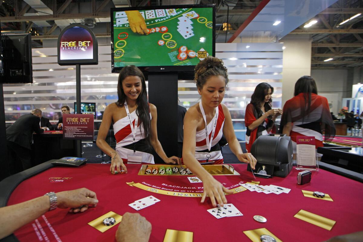 FILE - Attendants conduct play with the visitors over a Black Jack gaming table during the Global Gaming Expo Asia in Macao, May 23, 2013. Losing money due to COVID, the American casino giants that helped make Macao the "Las Vegas of Asia" face a fresh challenge: The tiny Chinese territory wants them to reduce its reliance on gambling by building theme parks and other tourist attractions. (AP Photo/Kin Cheung, File)