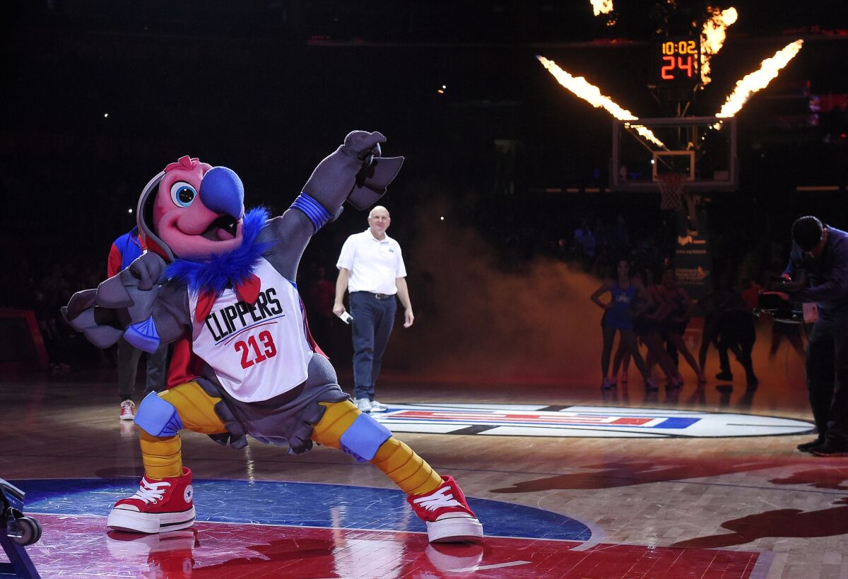 New Clippers mascot Chuck the Condor flexes as team owner Steve Ballmer stands in the background during halftime of a game on Feb. 29.