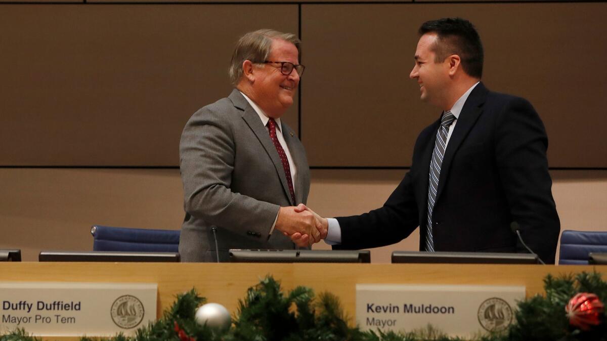 New Newport Beach Mayor Marshall “Duffy” Duffield, left, shakes hands with former mayor Kevin Muldoon at City Hall on Tuesday night.