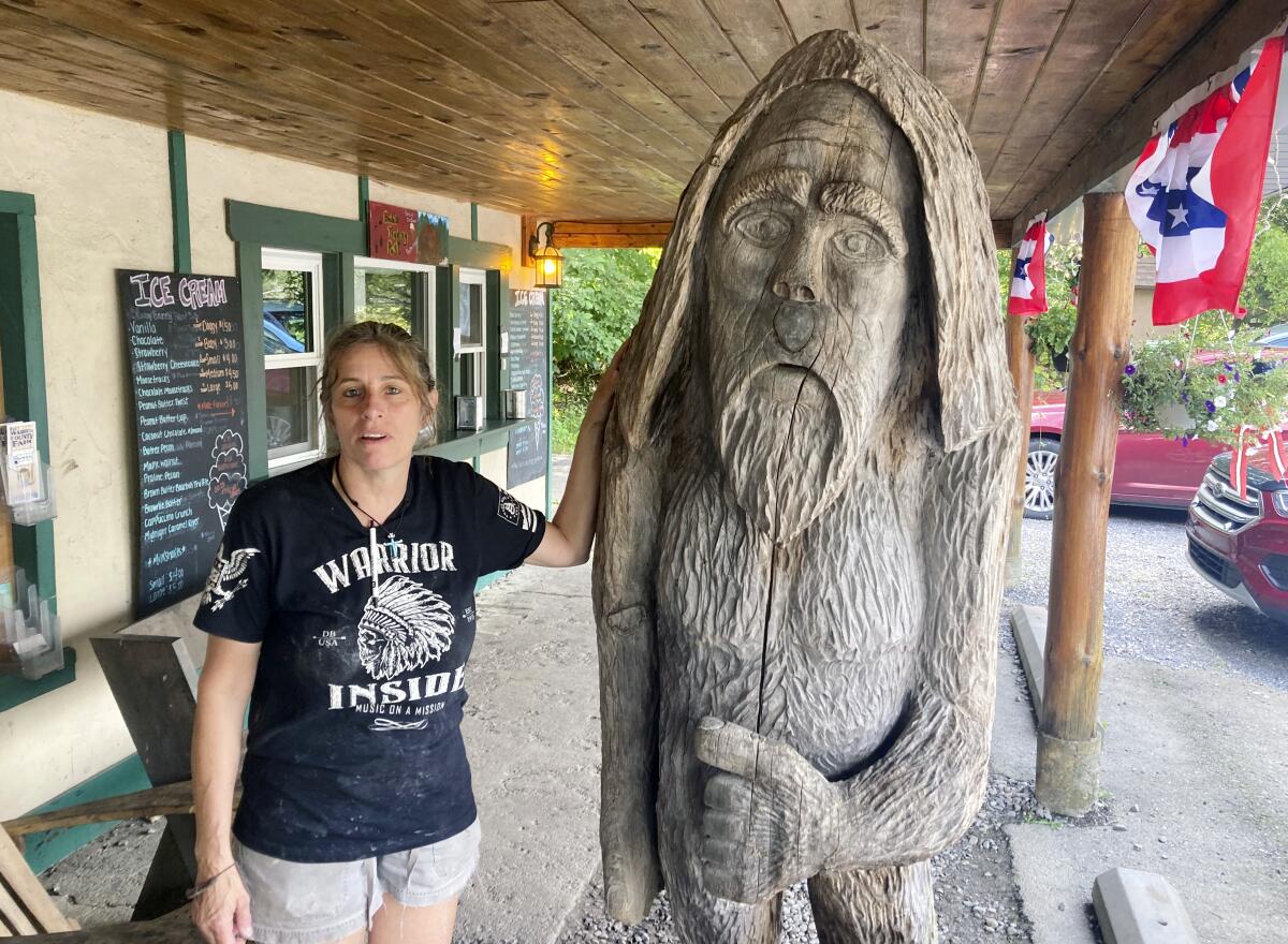 ARCHIVO - Pauline Bauer se apoya en una escultura de madera en Bob's Trading Post, 