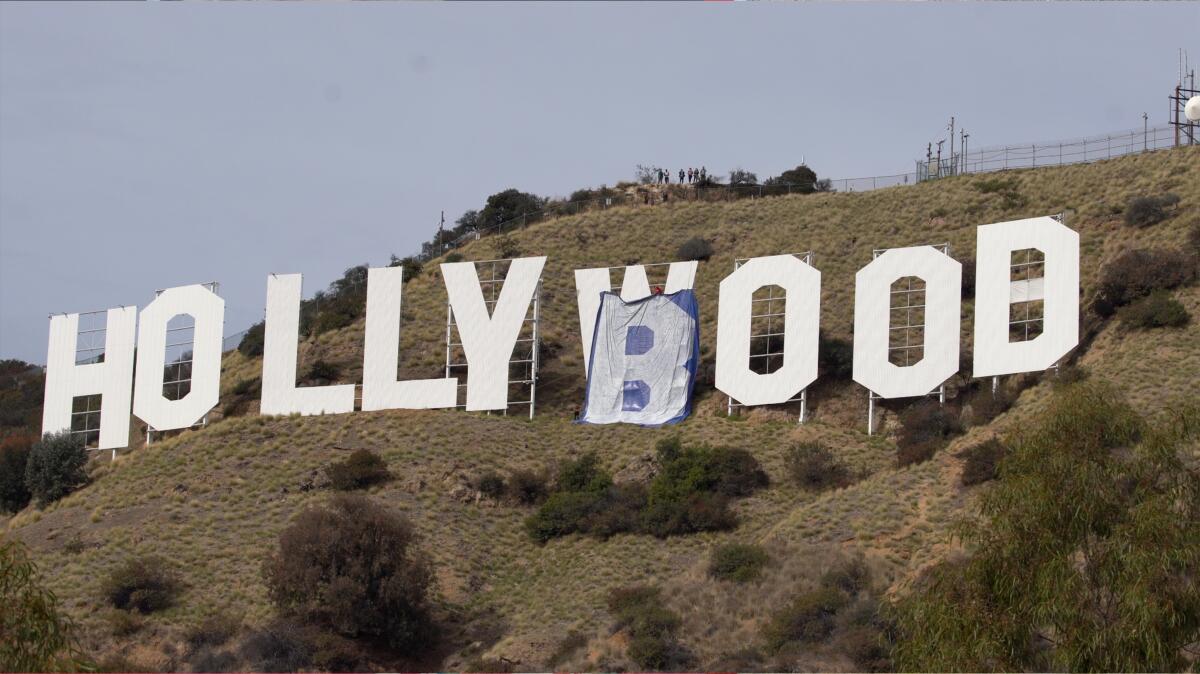 The Hollywood sign with a tarp with the letter "B" draped over the "W."